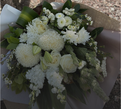 A bouquet by Angkor Flowers featuring white roses, chrysanthemums, and various greenery, arranged with brown wrapping paper.